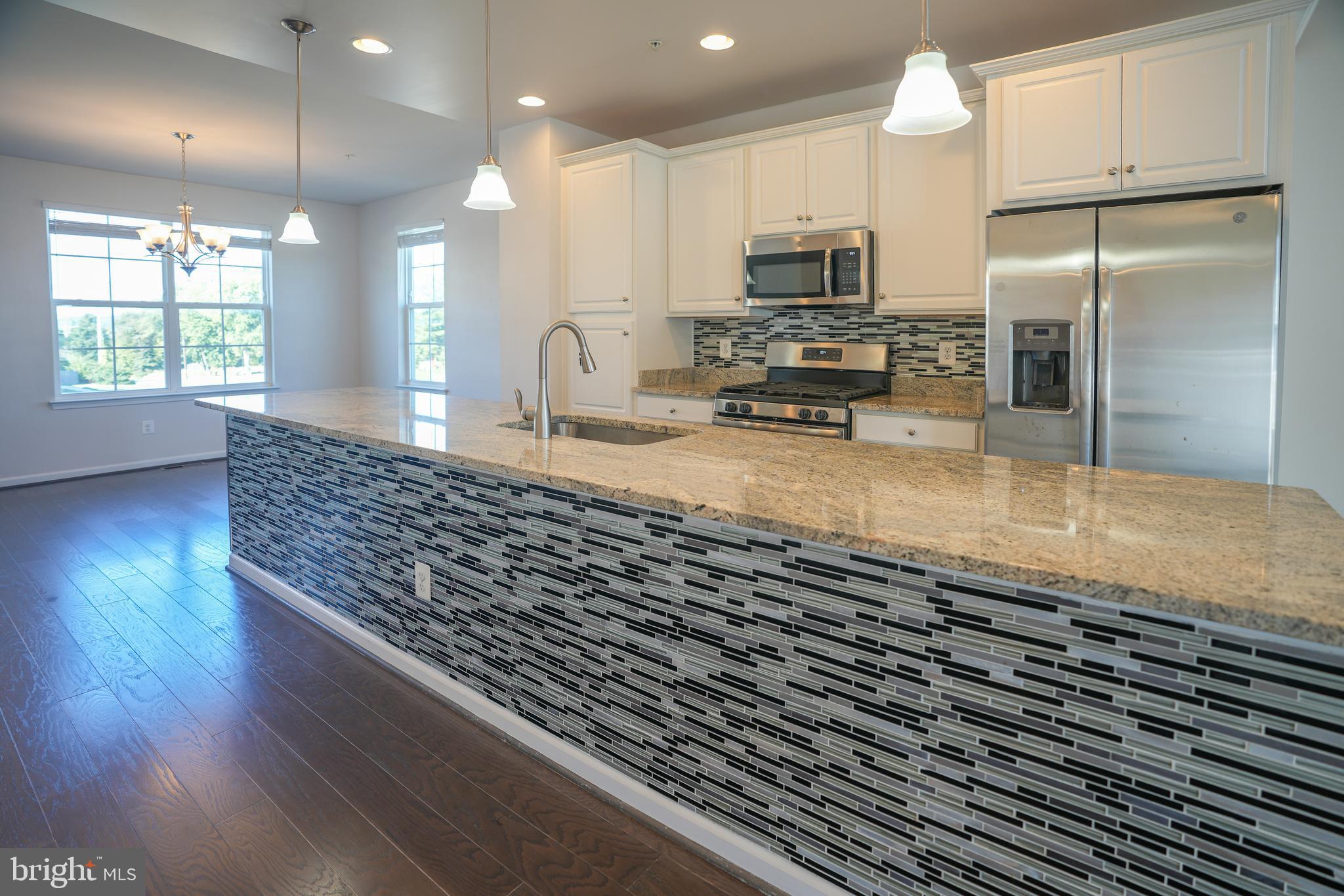 6150 Posey Street Frederick, MD 21703 - Photo 8 of 32 a kitchen with kitchen island granite countertop a stove a sink a refrigerator with wooden floor and cabinets