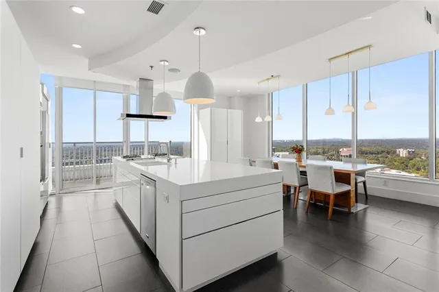 a large white kitchen with a large window and stainless steel appliances
