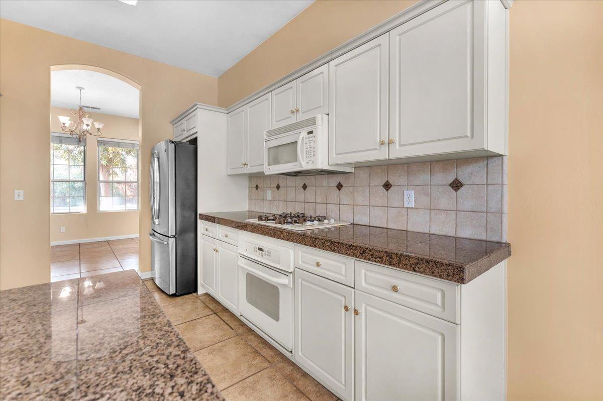 849 Megan Avenue Clovis, CA 93611 - Photo 9 of 53 a kitchen with granite countertop white cabinets and stainless steel appliances