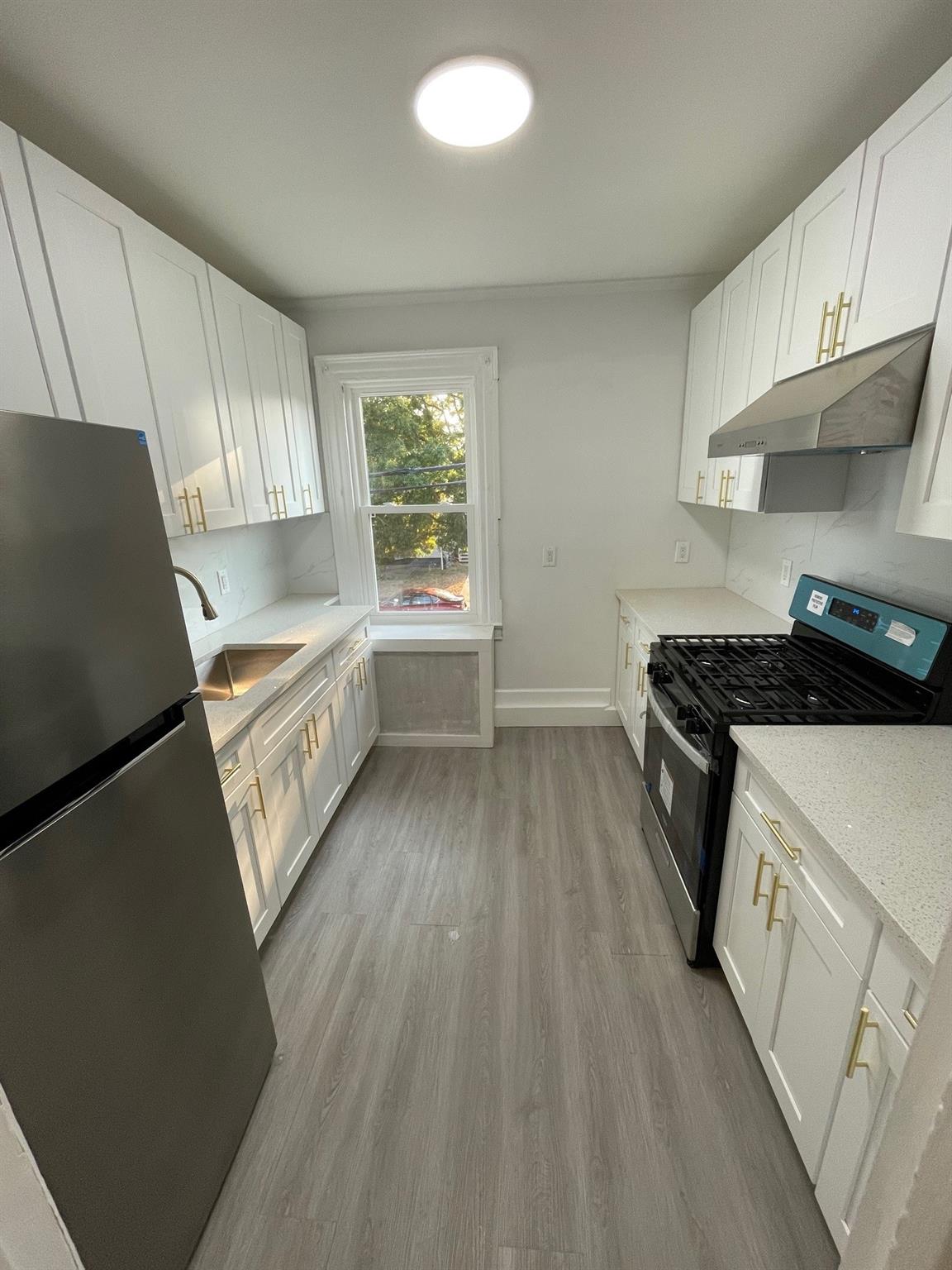 Kitchen with under cabinet range hood, white cabinetry, a sink, and appliances with stainless steel finishes
