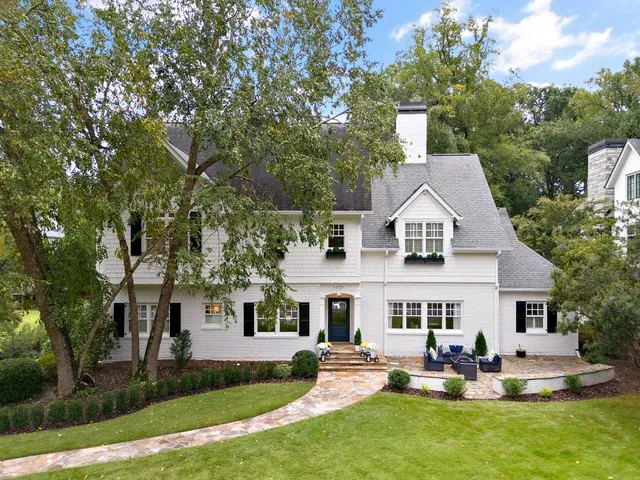 a front view of house with yard and trees in the background