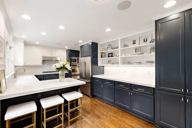 a kitchen with stainless steel appliances kitchen island granite countertop a refrigerator a sink and a stove with wooden floor