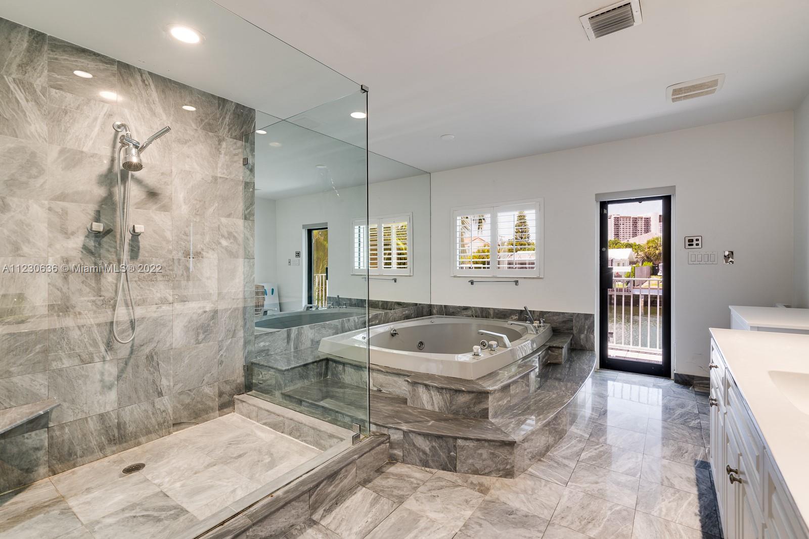 1922 Northeast 119th Road North Miami, FL 33181 - Photo 20 of 42 a spacious bathroom with a granite countertop tub sink a mirror a shower and a toilet