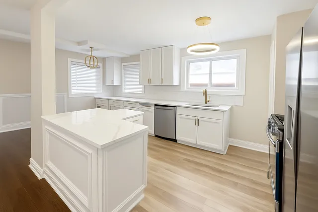 a kitchen with a sink a stove a refrigerator and white cabinets