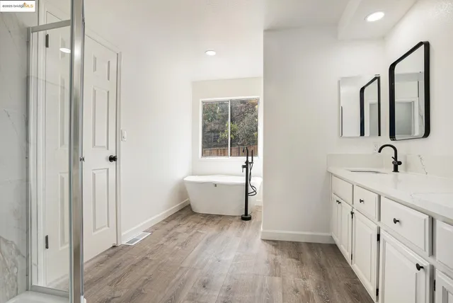a bathroom with a double vanity sink a mirror and a bathtub