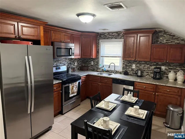 a kitchen with stainless steel appliances granite countertop a refrigerator a sink dishwasher a stove and a refrigerator