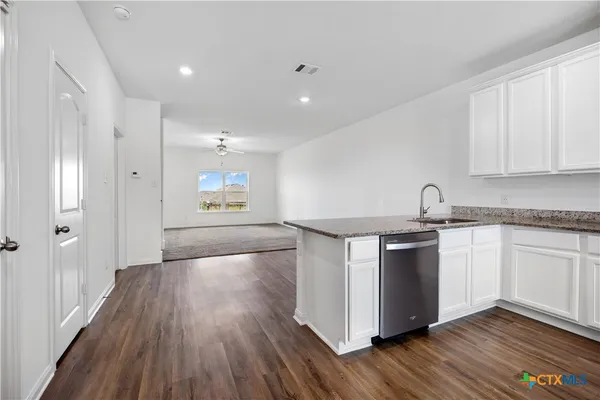 a kitchen with granite countertop a stove top oven a sink and wooden floors