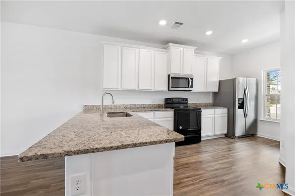 a kitchen with granite countertop a refrigerator and a stove top oven