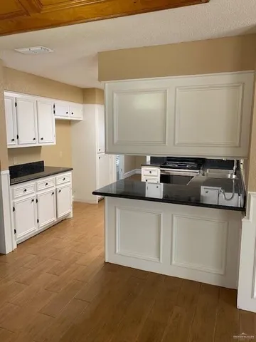 a kitchen with stainless steel appliances a stove a sink and white cabinets