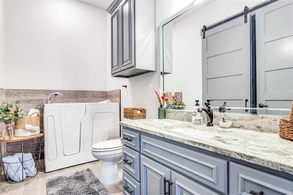 216 Deer Glade Court Azle, TX 76020 - Photo 28 of 40 a bathroom with a granite countertop toilet sink and mirror