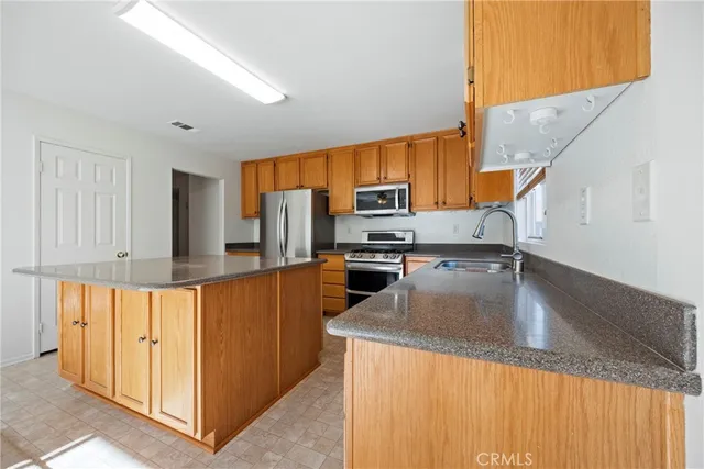 a kitchen with stainless steel appliances granite countertop a sink a stove and a refrigerator with wooden floor