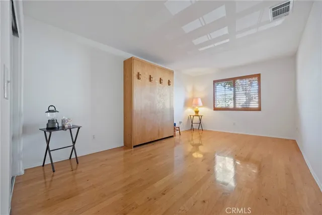 a view of an empty room with window and wooden floor