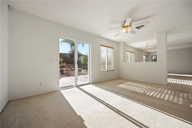 a view of an empty room with window and chandelier fan