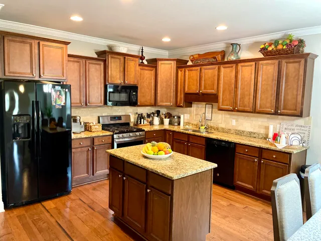 a kitchen with stainless steel appliances granite countertop a refrigerator a sink and a stove