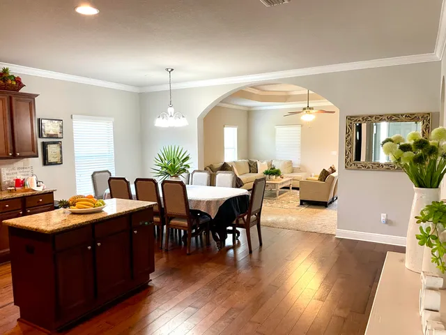 a view of a dining room and livingroom with furniture wooden floor a chandelier