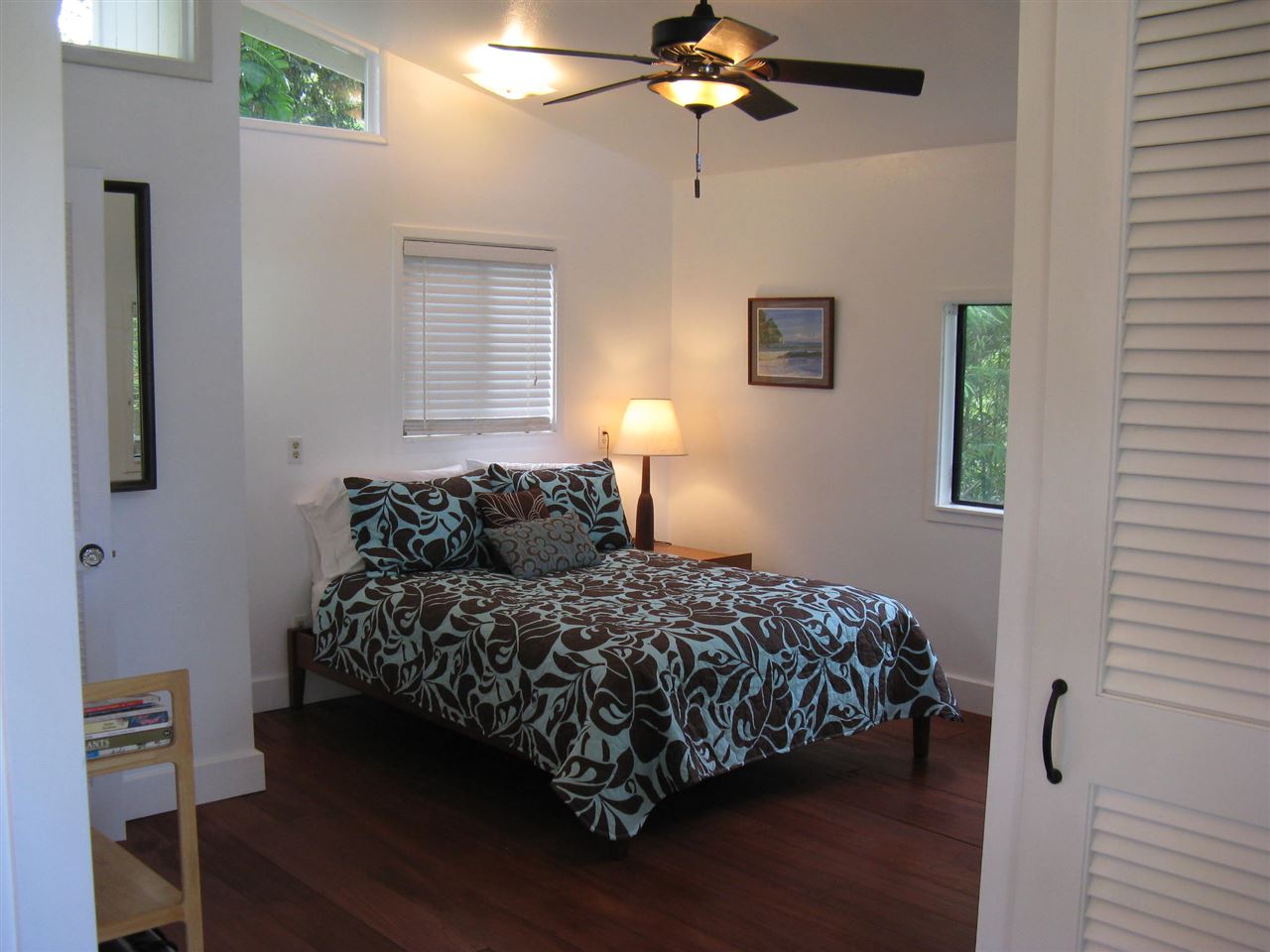 1061 Kokomo Road Haiku, HI 96708 - Photo 28 of 30 a bedroom with a bed and a chandelier