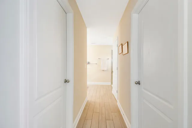 a view of a hallway with wooden floor and a bathroom