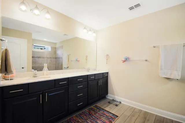 a spacious bathroom with a double vanity sink a mirror and a shower