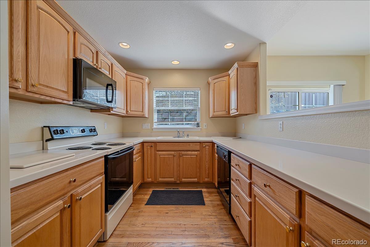 6310 Trailhead Road Highlands Ranch, CO 80130 - Photo 7 of 23 a kitchen with stainless steel appliances granite countertop a sink and dishwasher a stove top oven with wooden floor