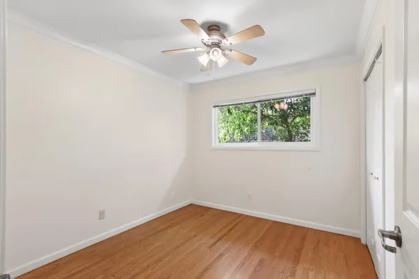 a view of an empty room with wooden floor and a window