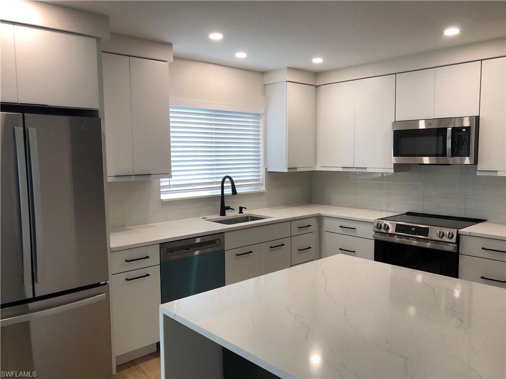 4150 Crayton Road, Unit B3 Naples, FL 34103 - Photo 5 of 19 a kitchen with stainless steel appliances a stove sink microwave refrigerator and cabinets