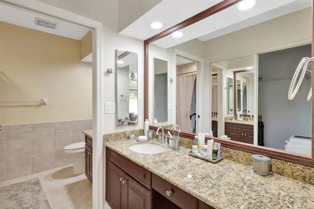 a bathroom with a granite countertop sink a toilet and a mirror