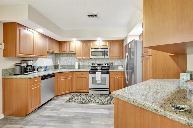 a kitchen with stainless steel appliances granite countertop a refrigerator stove and sink