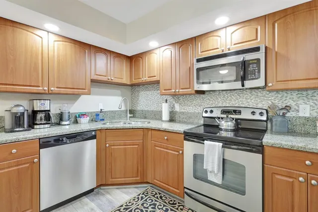 a kitchen with stainless steel appliances granite countertop a stove top oven a sink a dining table and chairs with wooden floor