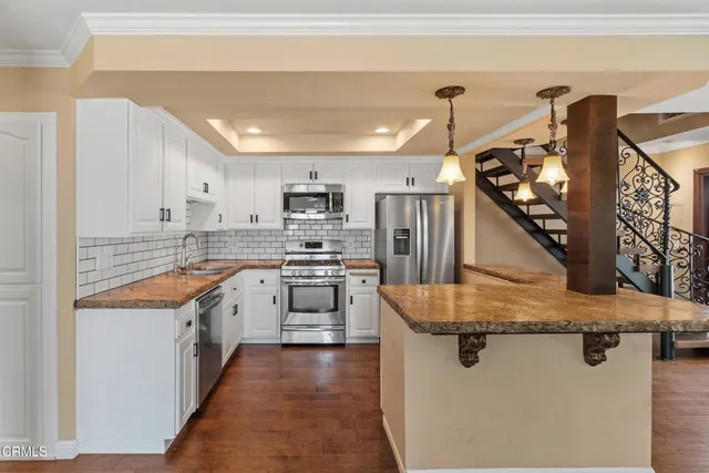 a kitchen with stainless steel appliances granite countertop a sink a stove and refrigerator