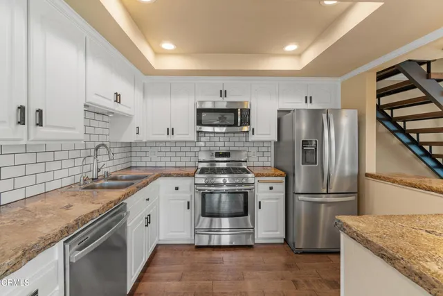 a kitchen with stainless steel appliances granite countertop a sink stove and refrigerator