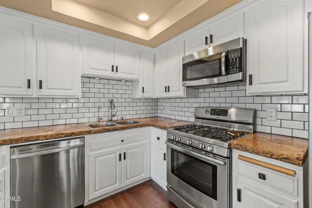 a kitchen with cabinets stainless steel appliances a sink and a wooden floor