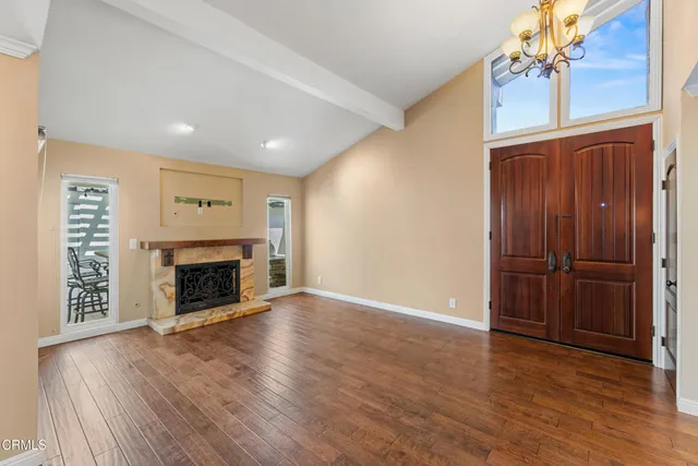an empty room with wooden floor fireplace and windows