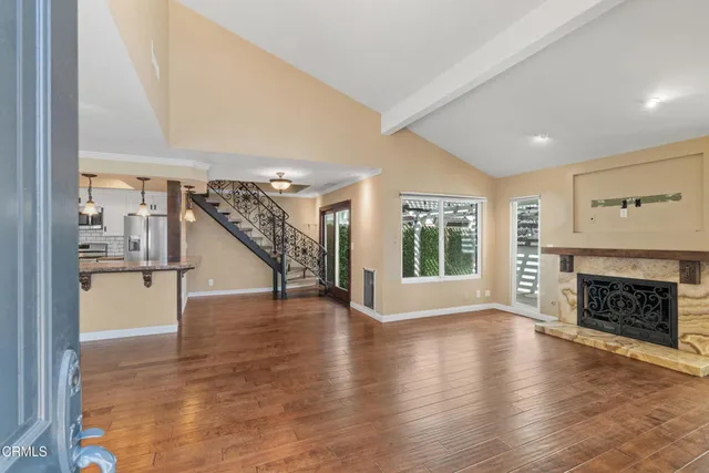 a view of an empty room with wooden floor fireplace and a window