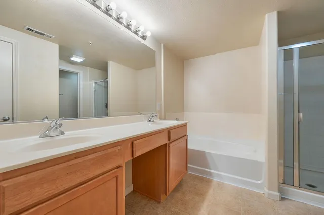 a bathroom with a sink double vanity granite tub and a mirror