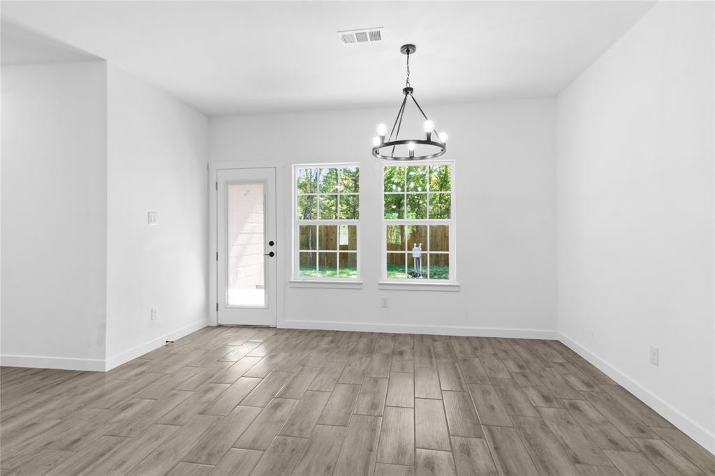 7520 Double Bridge Road Mabank, TX 75156 - Photo 13 of 32 Wood-finish plank flooring, white walls, black chandelier, double-pane windows, and a glass-paneled exterior door
