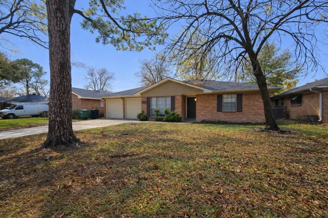 a front view of a house with a garden and tree