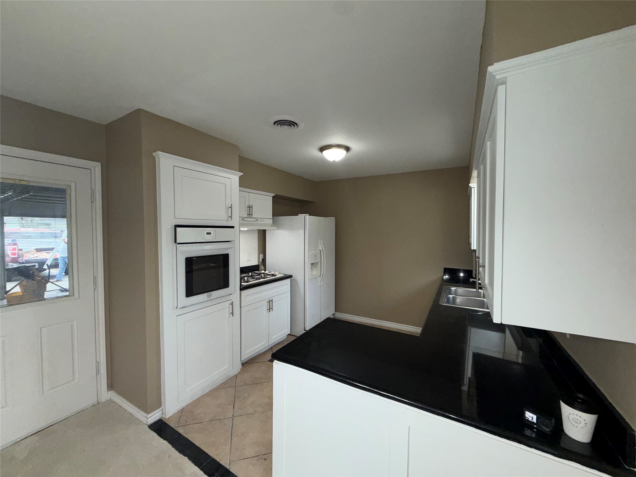 7306 Troulon Drive Houston, TX 77074 - Photo 6 of 16 a kitchen with granite countertop white cabinets and refrigerator