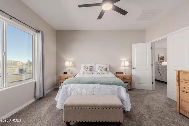 a bedroom with a large bed and a chandelier fan