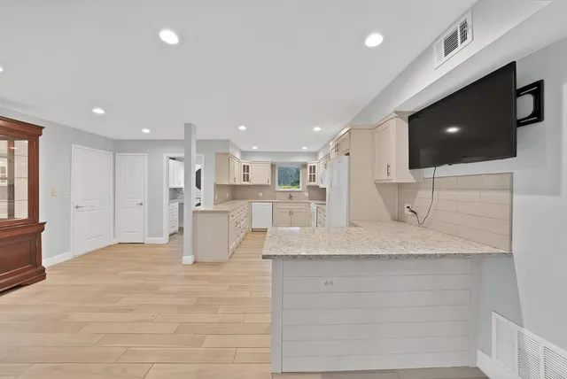 a dining room with stainless steel appliances kitchen island granite countertop a dining table chairs and a refrigerator