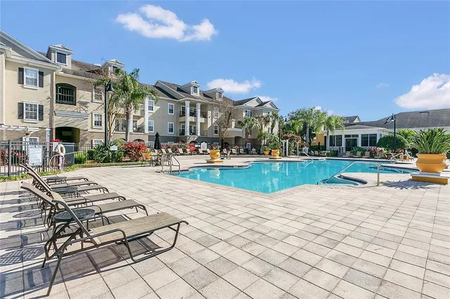 a view of pool with lawn chairs and tables