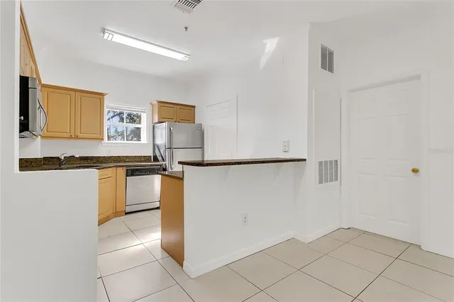 a kitchen with granite countertop a refrigerator and cabinets