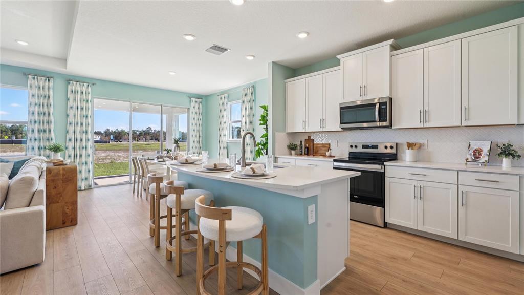 5224 Southwest 40th Circle Ocala, FL 34474 - Photo 3 of 48 a kitchen with stainless steel appliances granite countertop a stove a sink a microwave a dining table and chairs