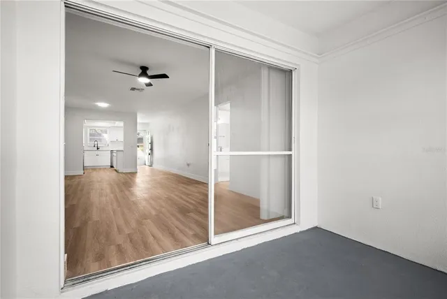a view of empty room with wooden floor and fan