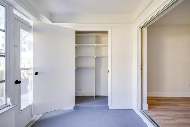 a view of an empty room with window and wooden floor