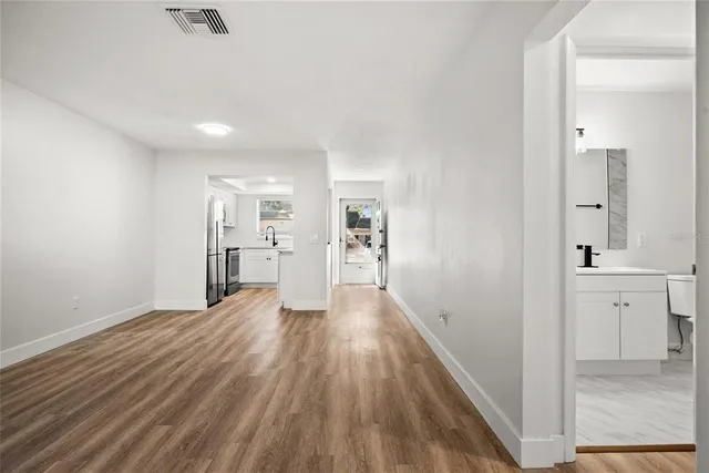 a view of a hallway with wooden floor and a kitchen