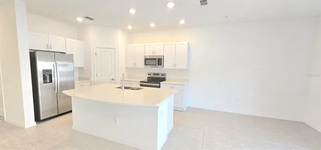 a kitchen with kitchen island a sink stainless steel appliances and white cabinets