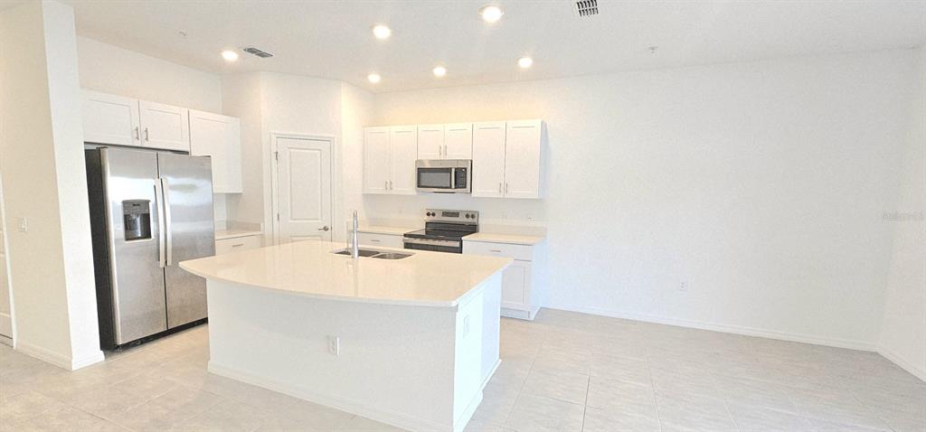5000 Revolutionary Way St. Cloud, FL 34769 - Photo 11 of 32 a kitchen with kitchen island a sink stainless steel appliances and white cabinets