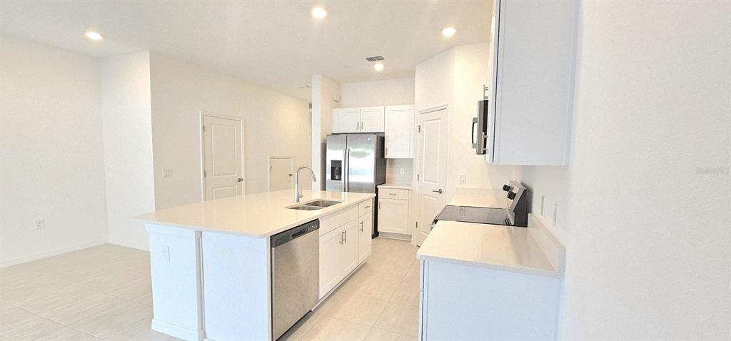 5000 Revolutionary Way St. Cloud, FL 34769 - Photo 14 of 32 a large white kitchen with a sink and dishwasher with white countertops