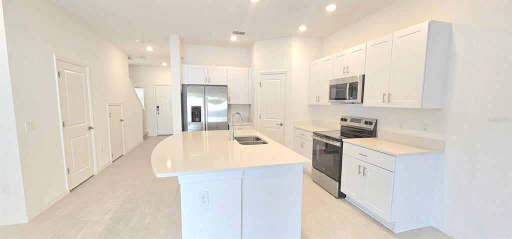 5000 Revolutionary Way St. Cloud, FL 34769 - Photo 15 of 32 a kitchen with a sink a stove a refrigerator and white cabinets