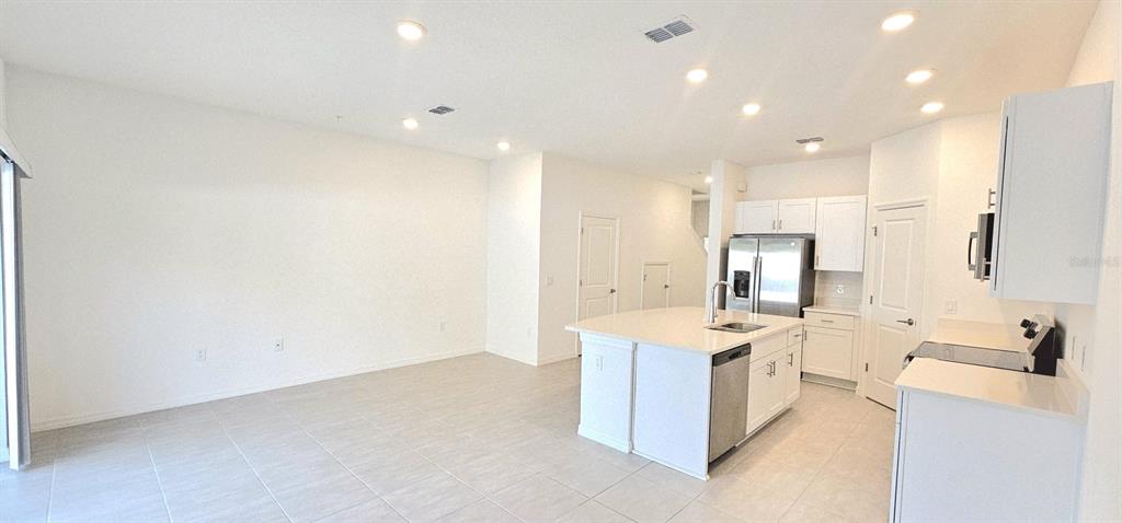 5000 Revolutionary Way St. Cloud, FL 34769 - Photo 16 of 32 a view of a kitchen with kitchen island a sink stainless steel appliances and white cabinets